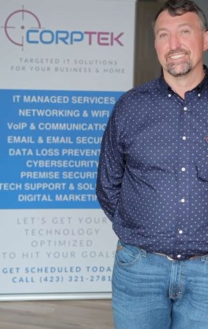 Jeremy Jarvis standing in office with a Corptek Banner standing behind him listing our services.